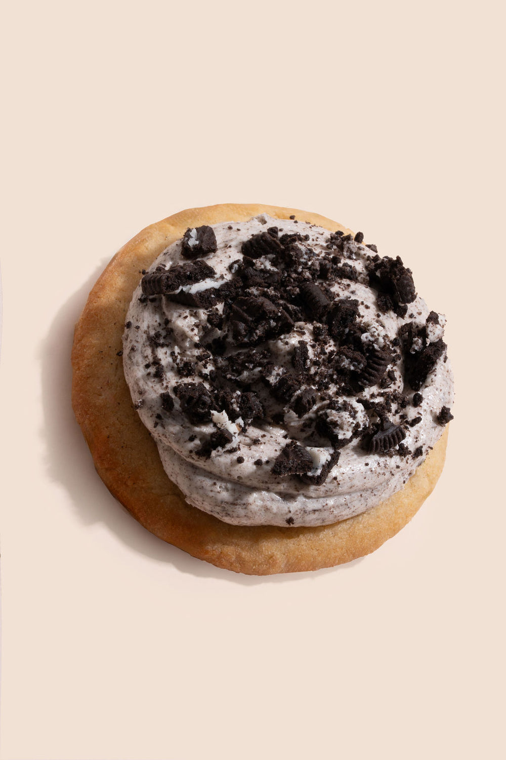 Base de vainilla suave y dorada, cubierta con una crema de galleta estilo Oreo y trozos crujientes por encima.