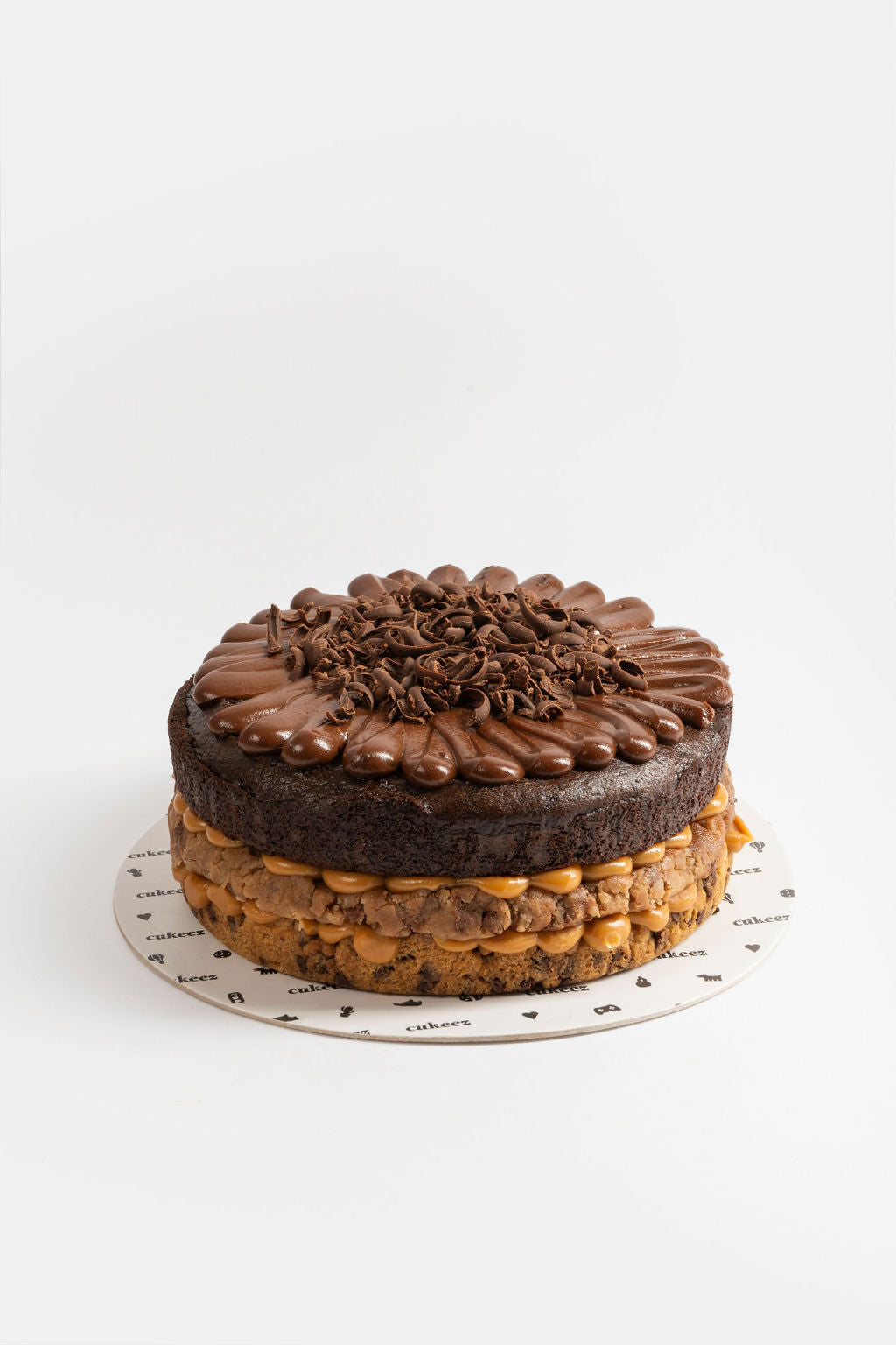 Torta con una capa de la masa de galleta de vainilla melcochuda con chispas de chocolate, una capa de cookiedough y seguido de una capa de torta de chocolate con relleno de manjar de olla y fudge de olla