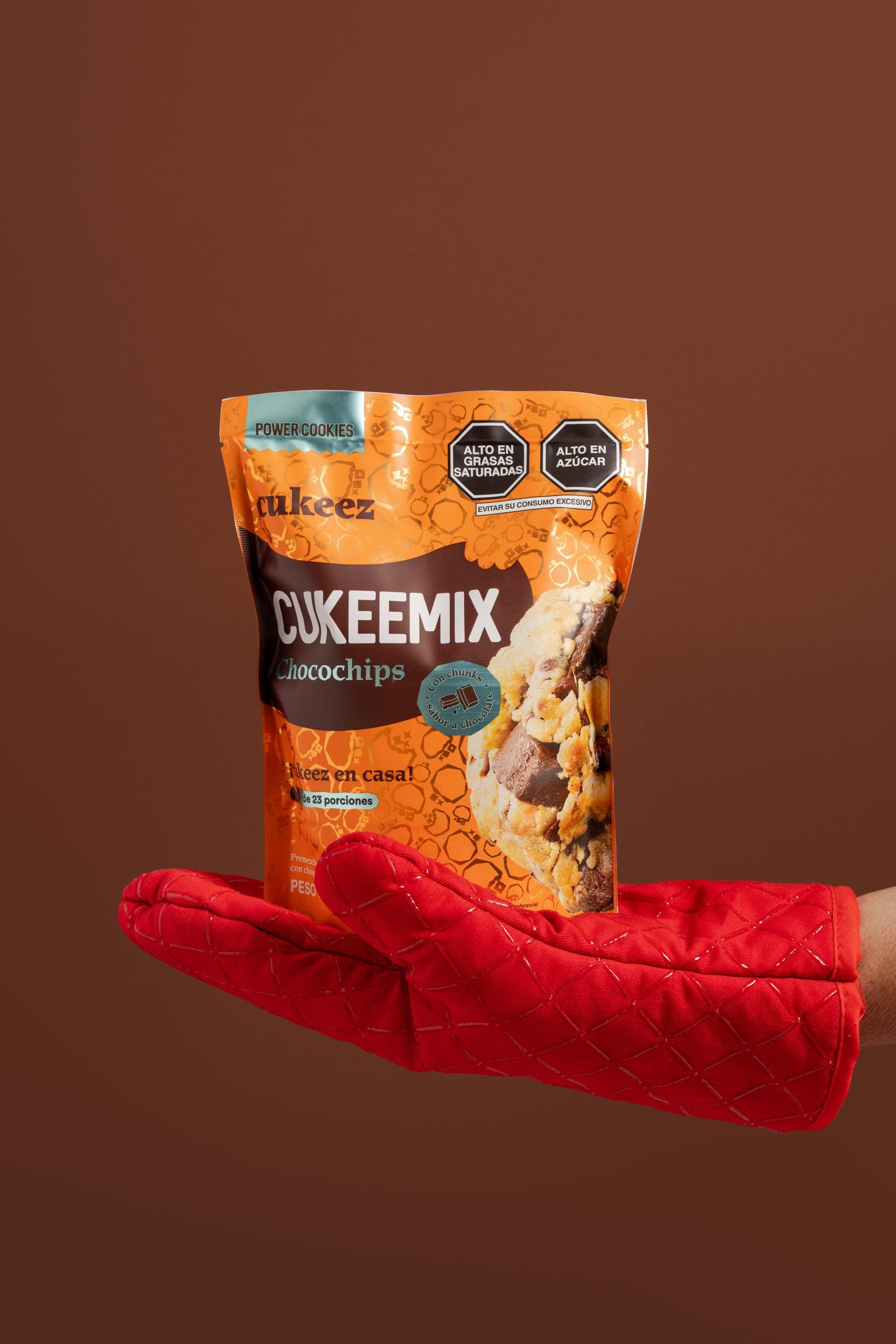 Una mano con un guante rojo sosteniendo la pre mezcla de galletas chocochips