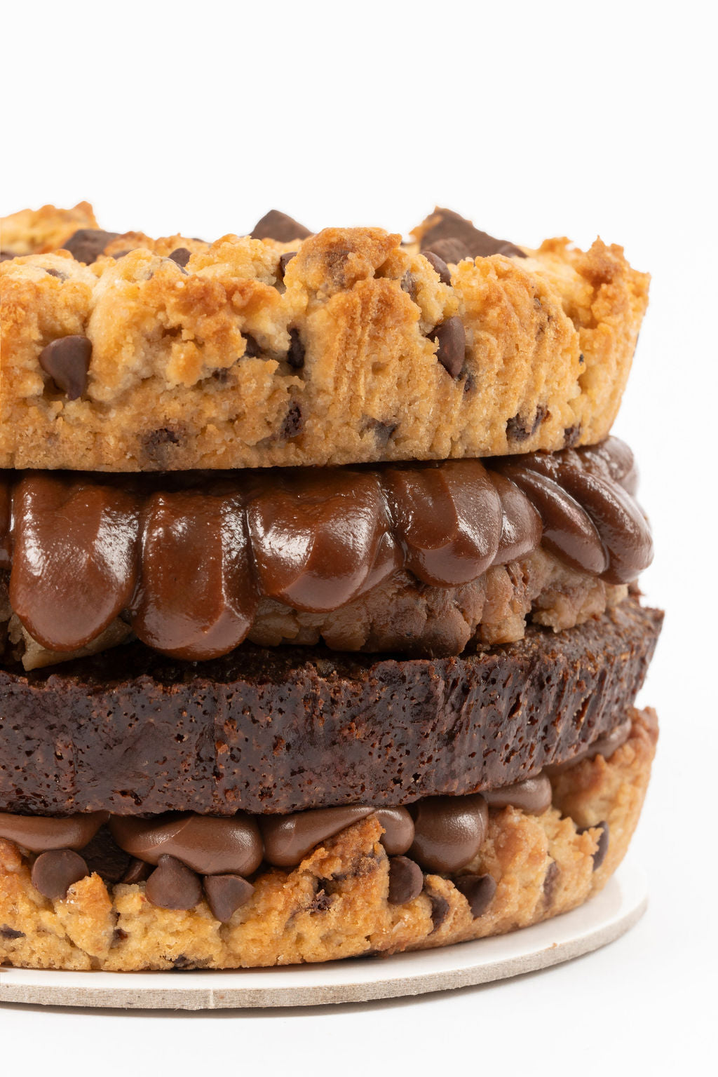 Torta de galleta de dos capas de galleta de vainilla con chips y trozos de chocolate, una capa de nutella, una capa de brownie melcochudo, una capa de cookiedough y una capa de fudge de olla.